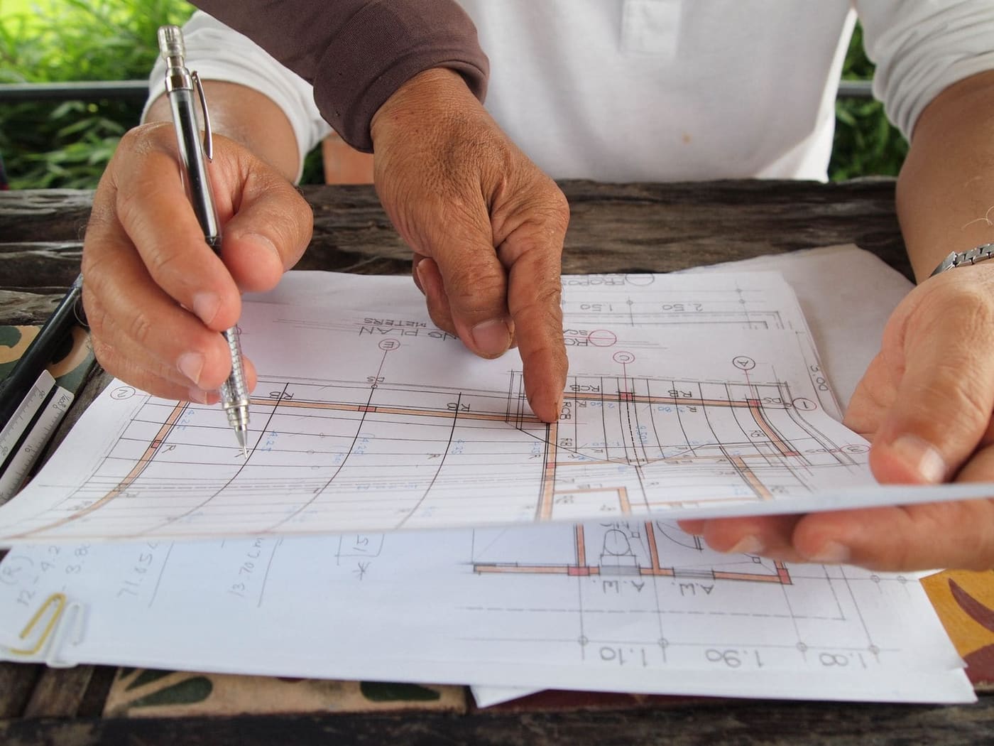 Hands marking up a printed floor plan with a pen