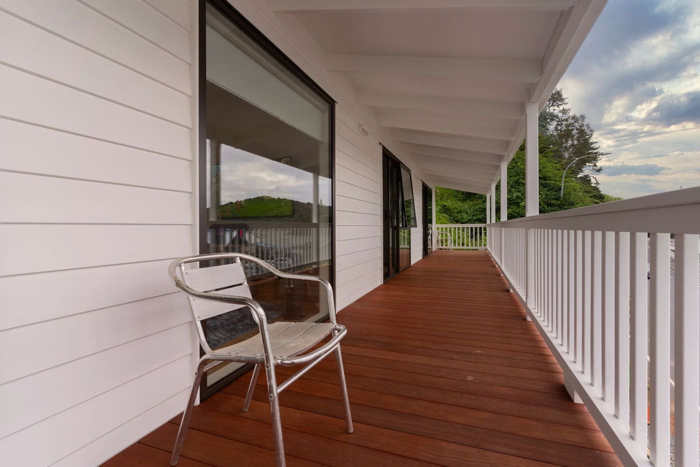 A long covered verandah with a hardwood deck and white timber railings