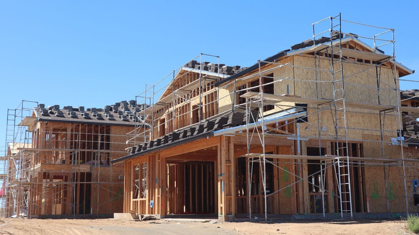 The timber frame of a two-storey extension going up behind scaffolding