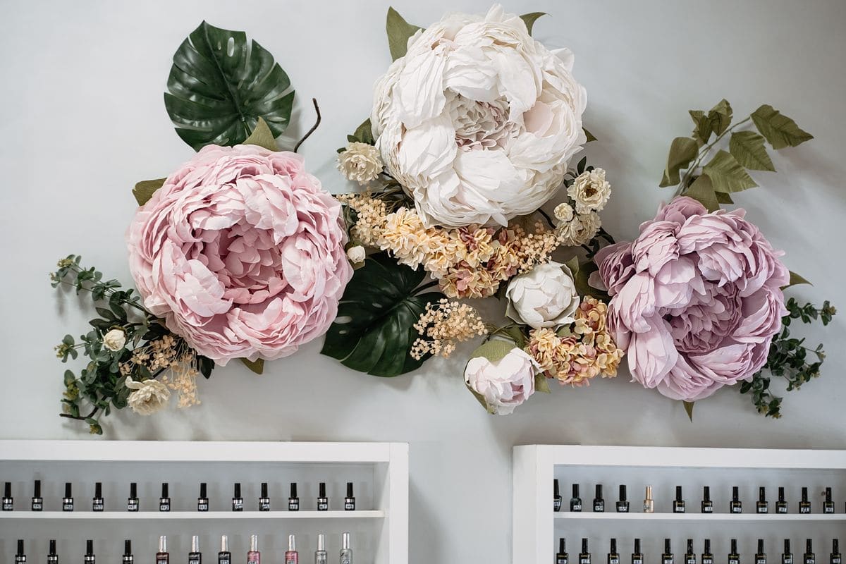 Pink and white paper flowers above shelves of polish
