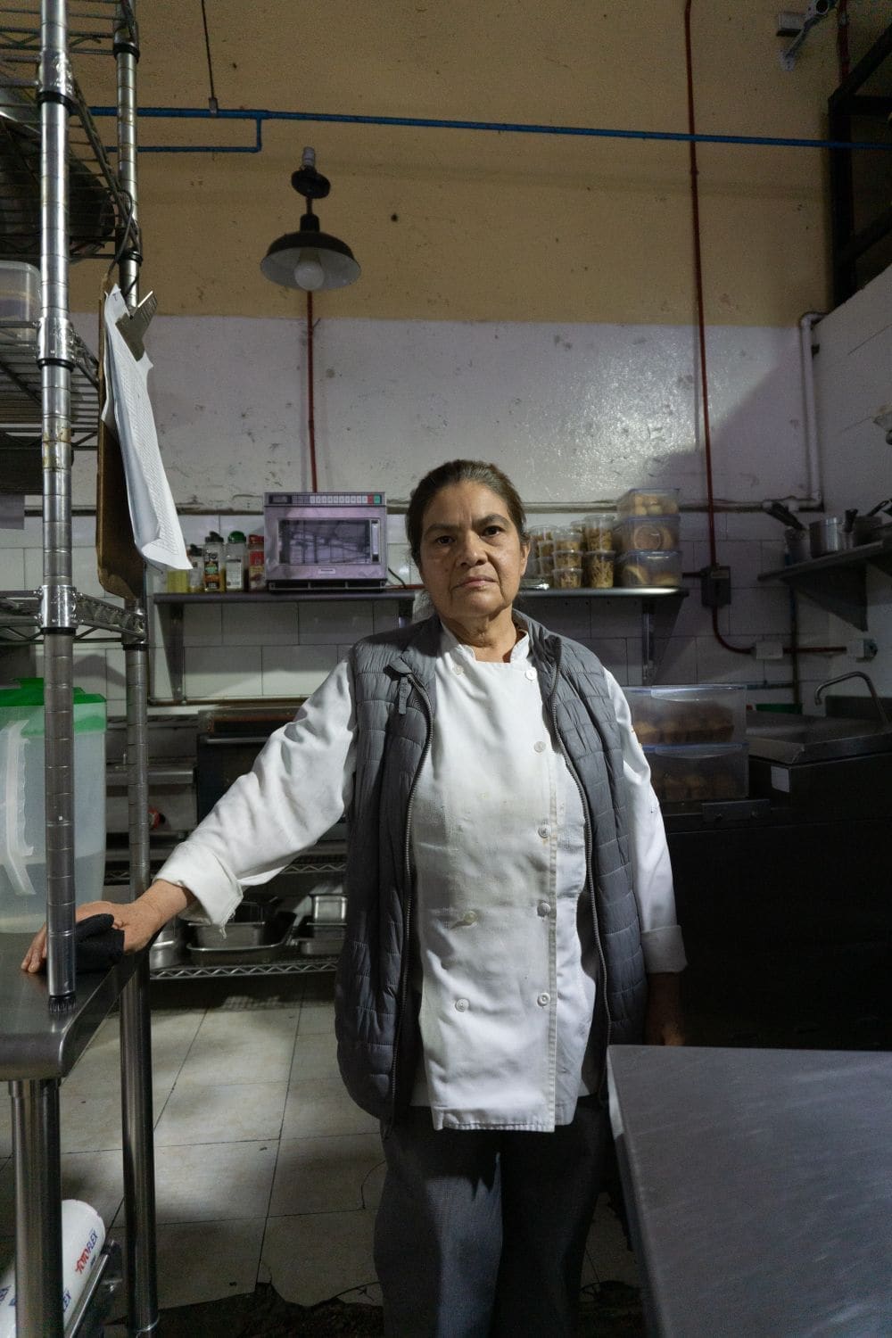 The head chef in a white jacket standing in the kitchen