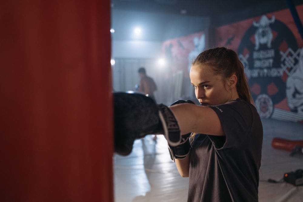 A woman throwing a punch at a heavy bag