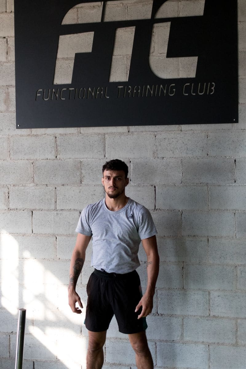A coach in a grey T-shirt standing against a block wall