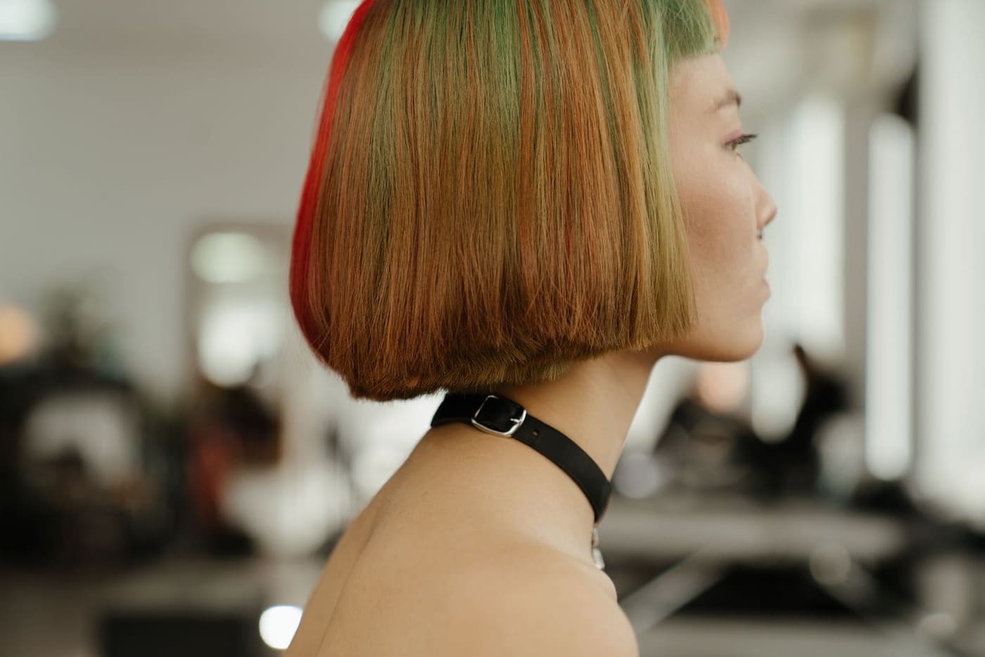 A woman with a sleek copper and blonde bob, seen in profile