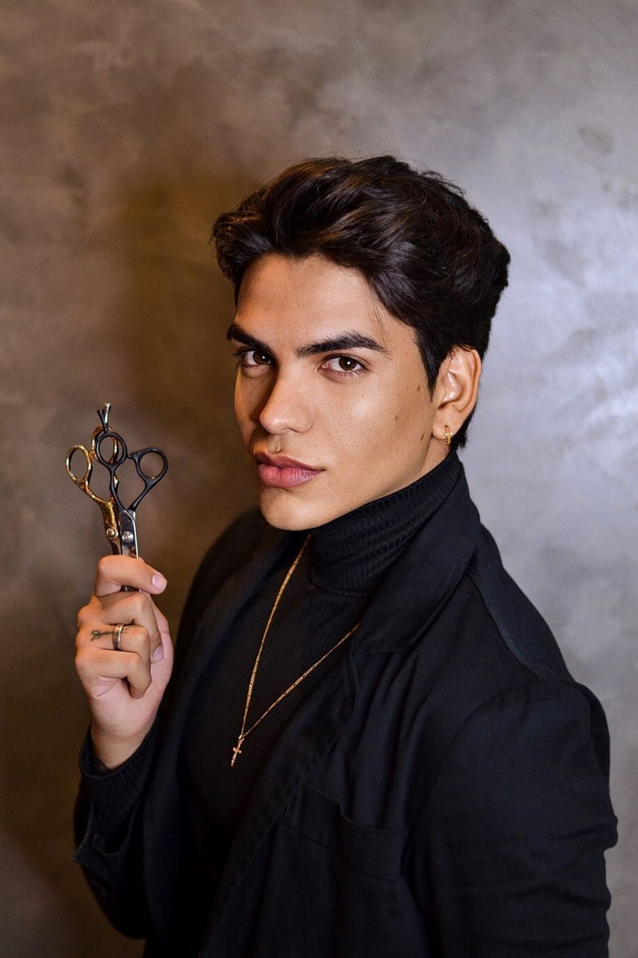 A stylist in a black turtleneck holding scissors