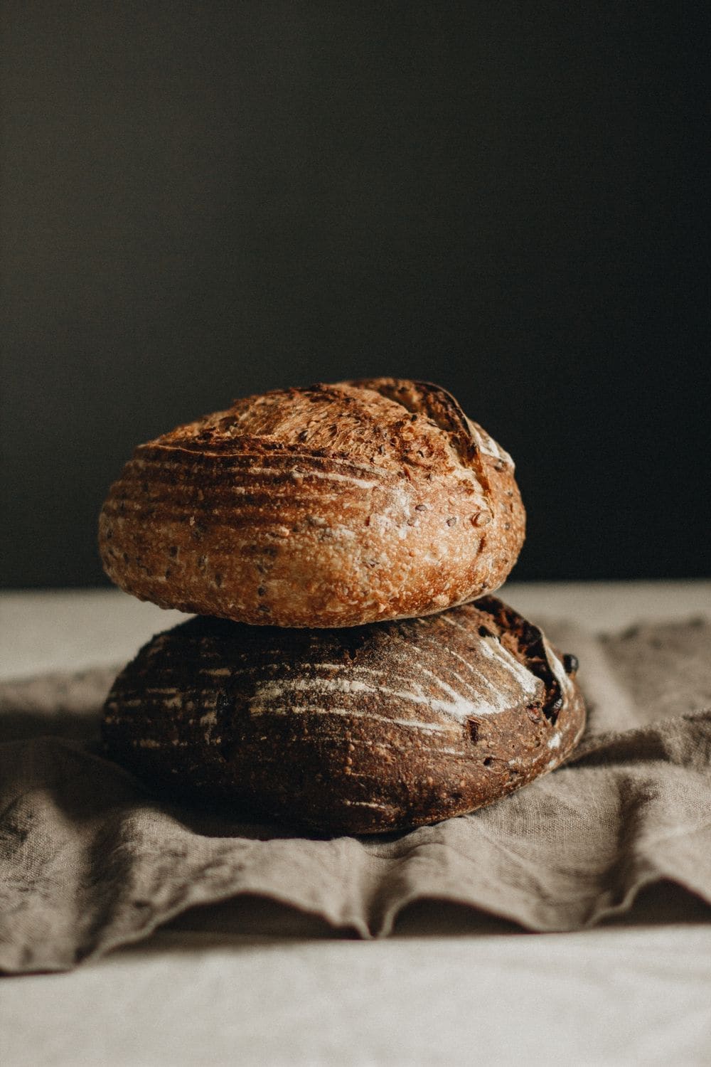 Two dark-crusted sourdough loaves stacked on a table
