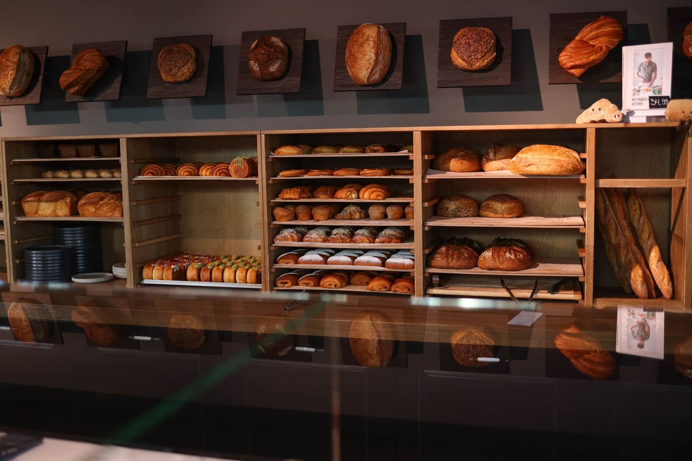 Wooden shelves stacked with loaves and pastries in a dim bakery