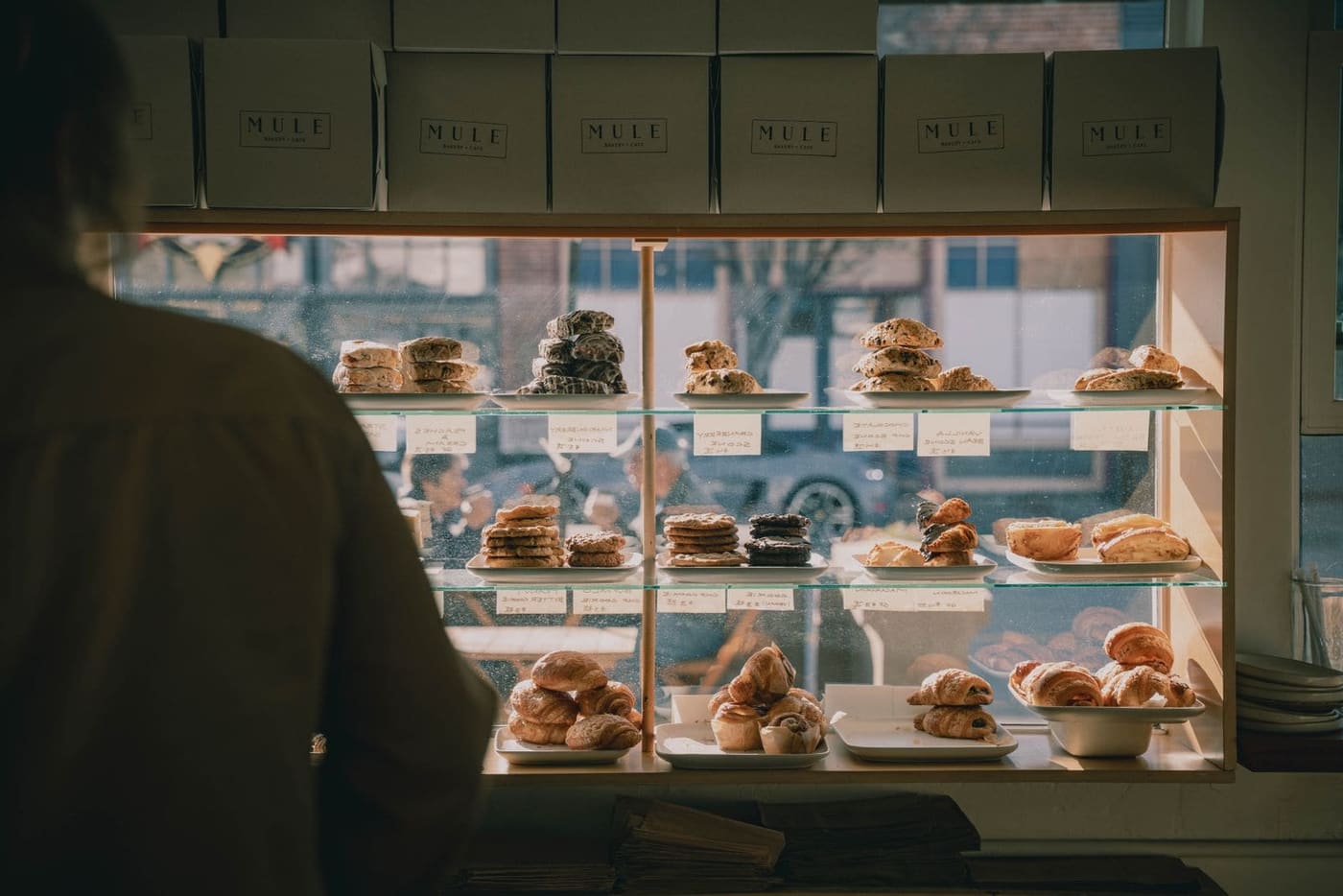 A bakery window with pastries on glass shelves