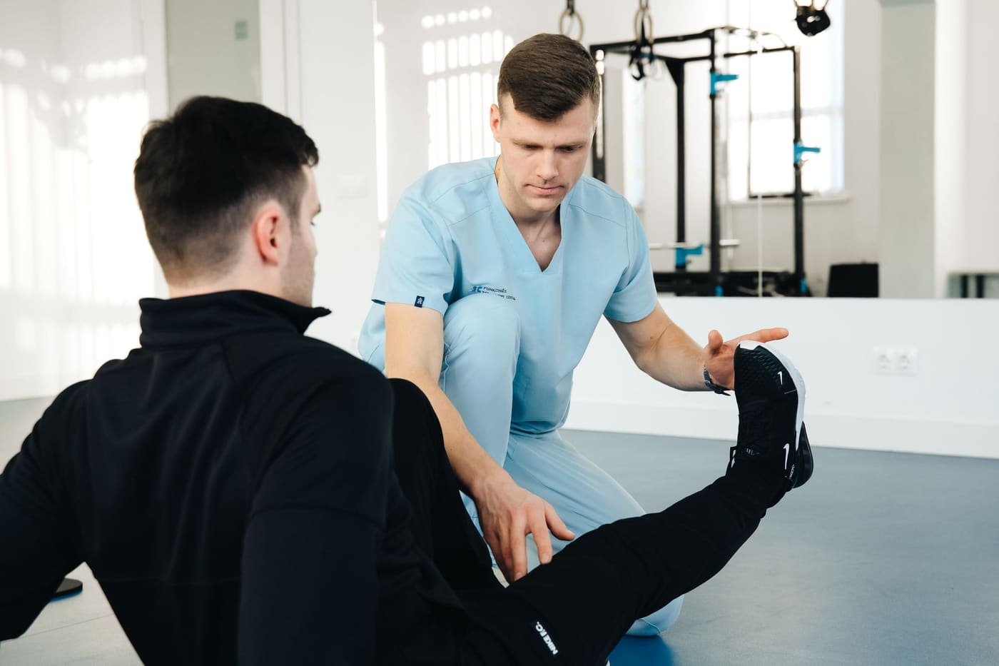 A physiotherapist stretching a patient's leg in a bright treatment room