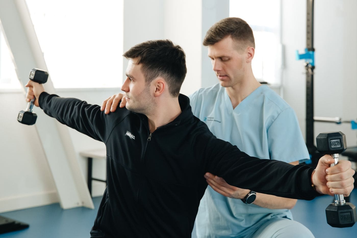A physiotherapist guiding a patient through a dumbbell exercise