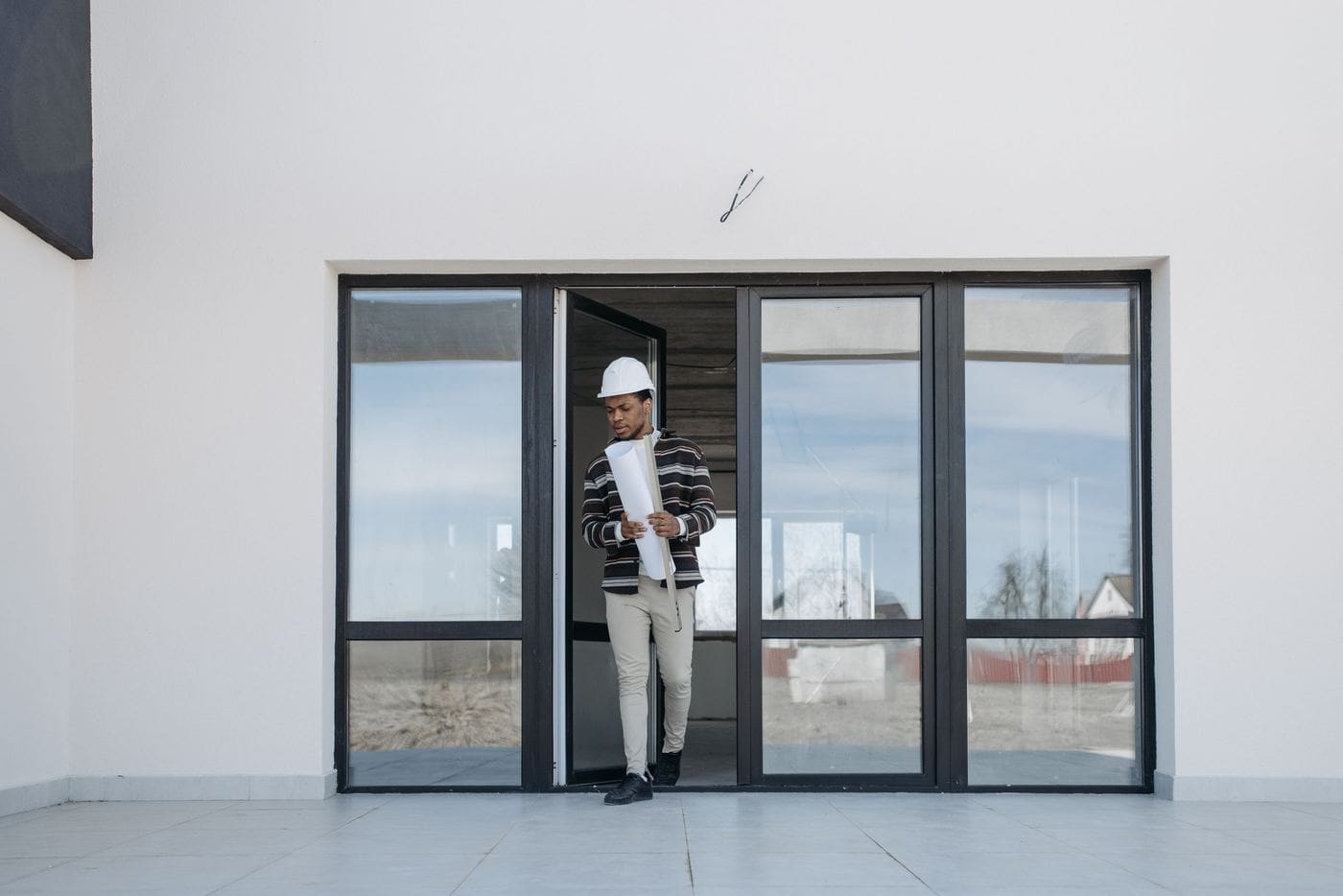 A finished room with tall glass doors and a builder standing in the doorway