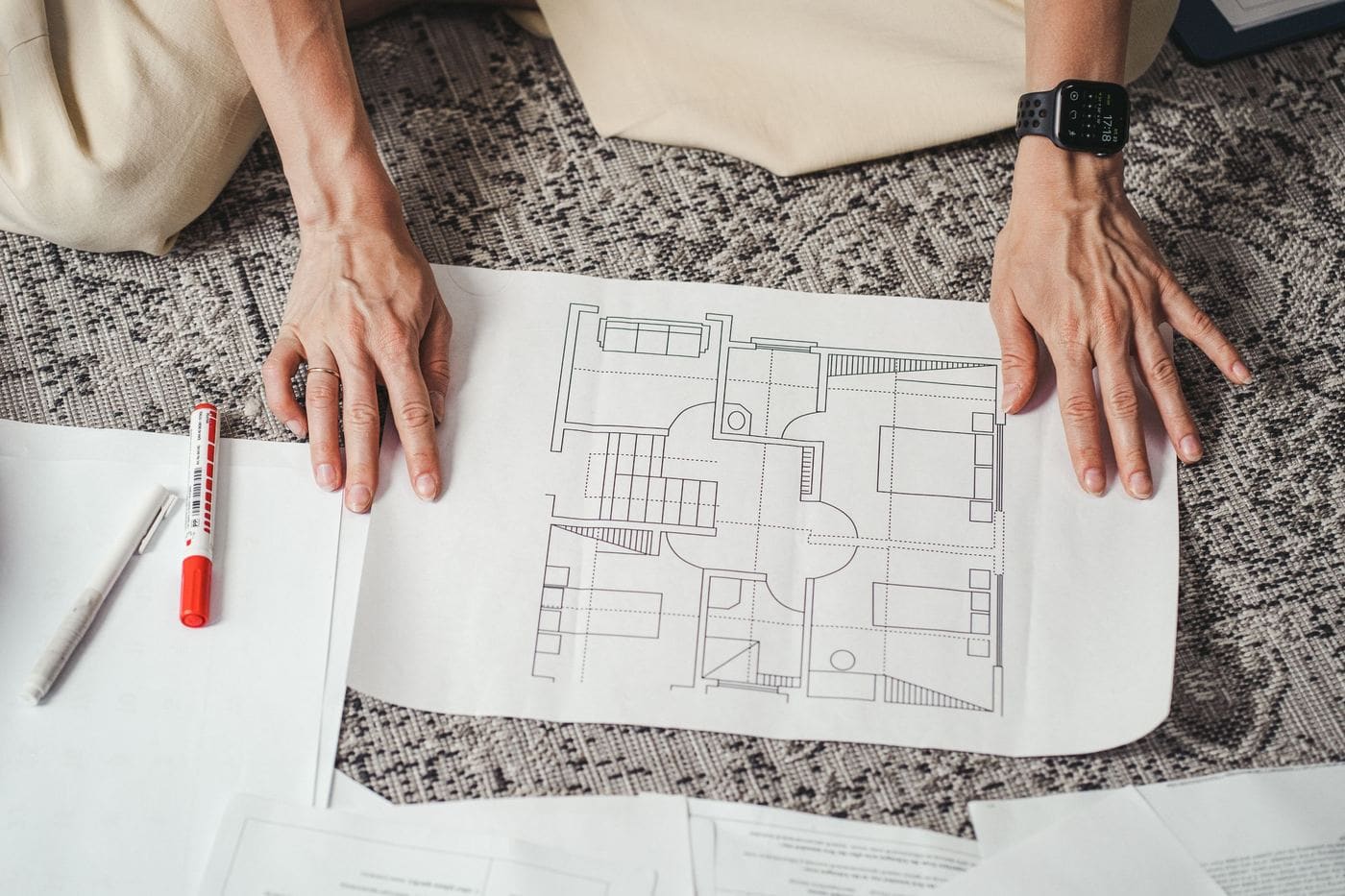 Hands resting on a printed floor plan, with a pen beside it