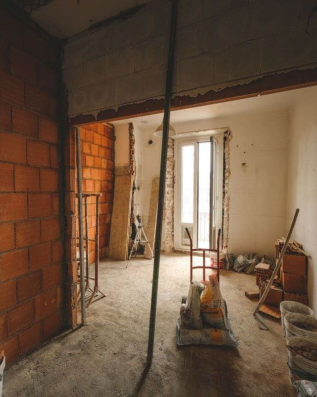 A room stripped back to brick during a renovation, with tools and timber on the floor
