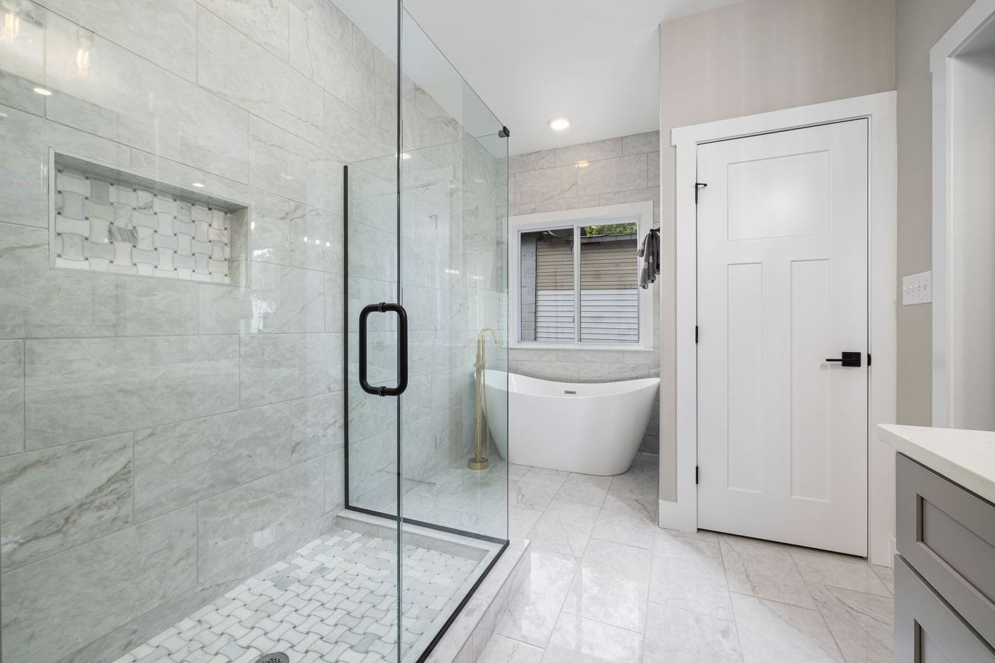 A marble-look bathroom with a walk-in shower and a freestanding bath