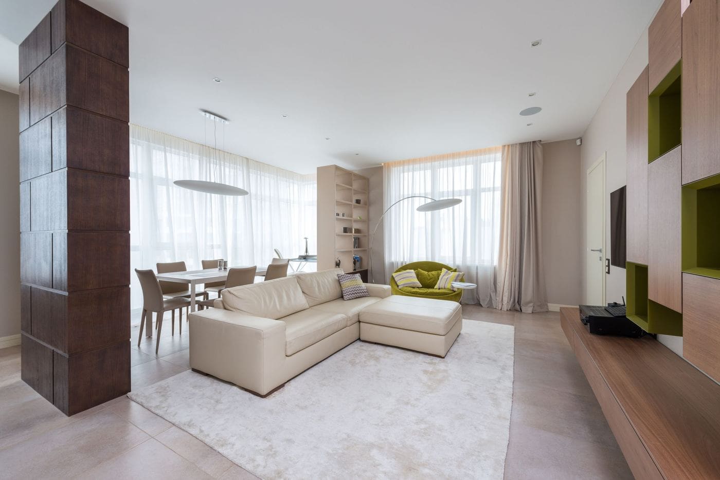 A bright living room with a white sofa, sheer curtains and timber panelling