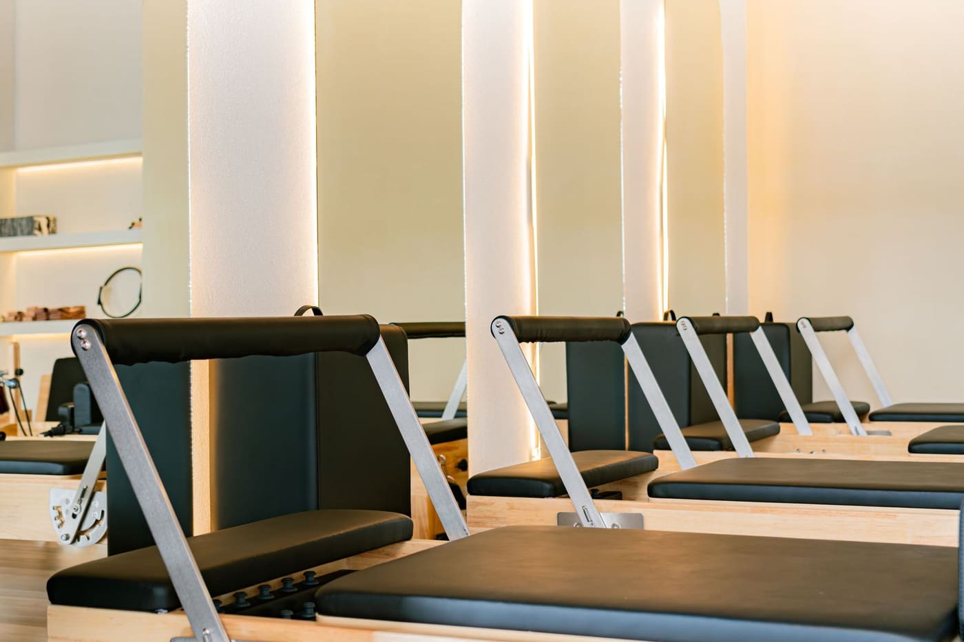 A row of pilates reformers in a warm, softly lit studio