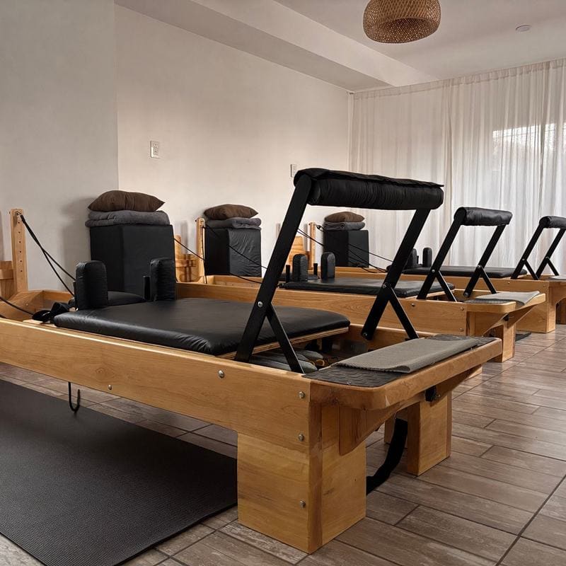 Wooden pilates reformers lined up in a bright studio