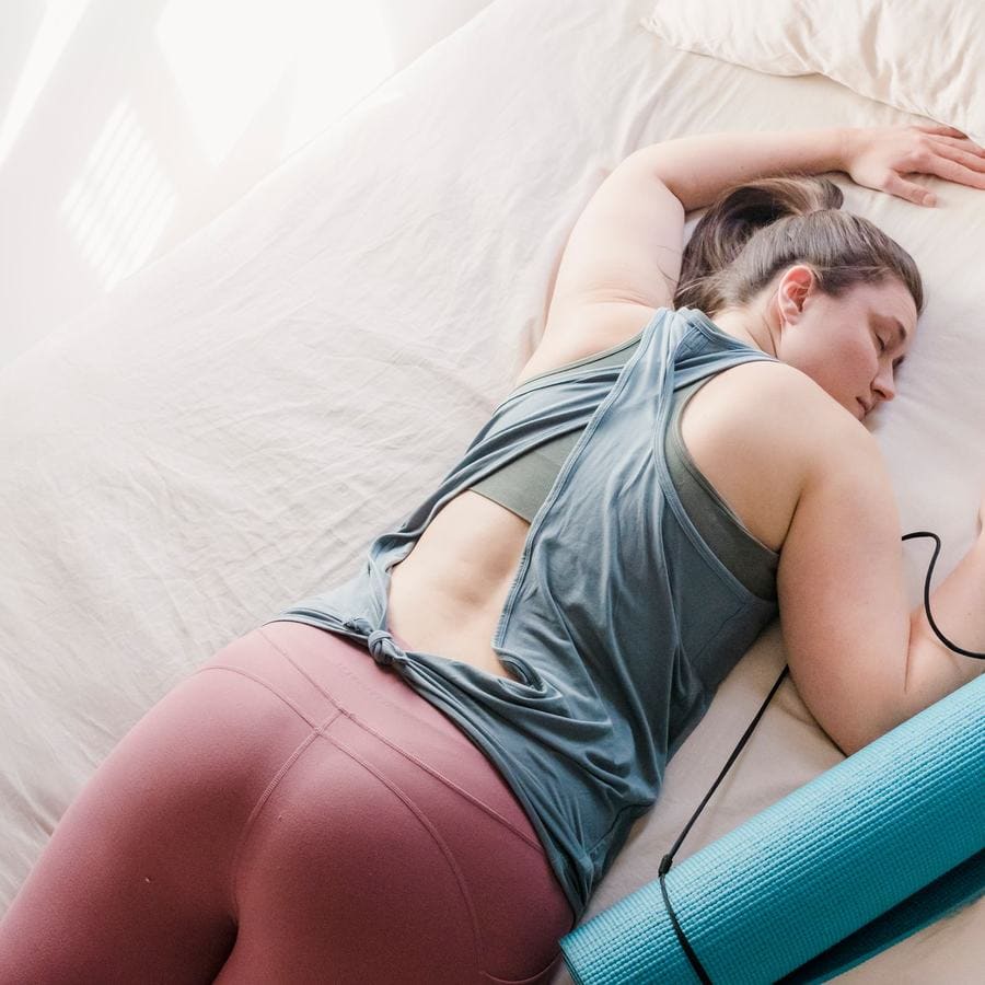 A woman resting over a bolster in a supported yoga pose