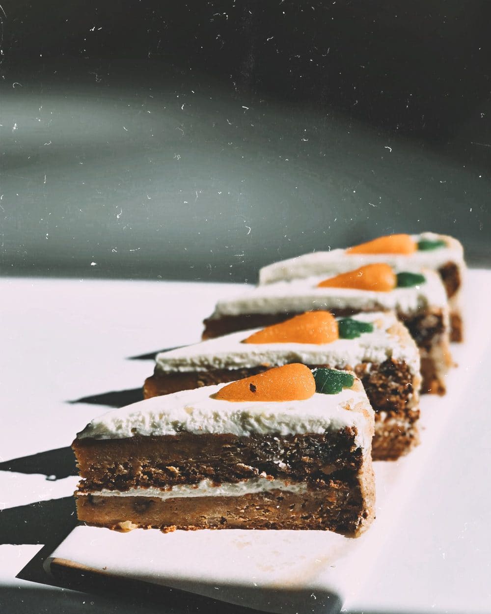 Slices of carrot cake with cream cheese icing in a row