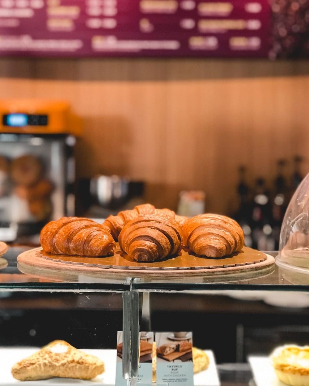 Croissants on a cake stand in a glass counter