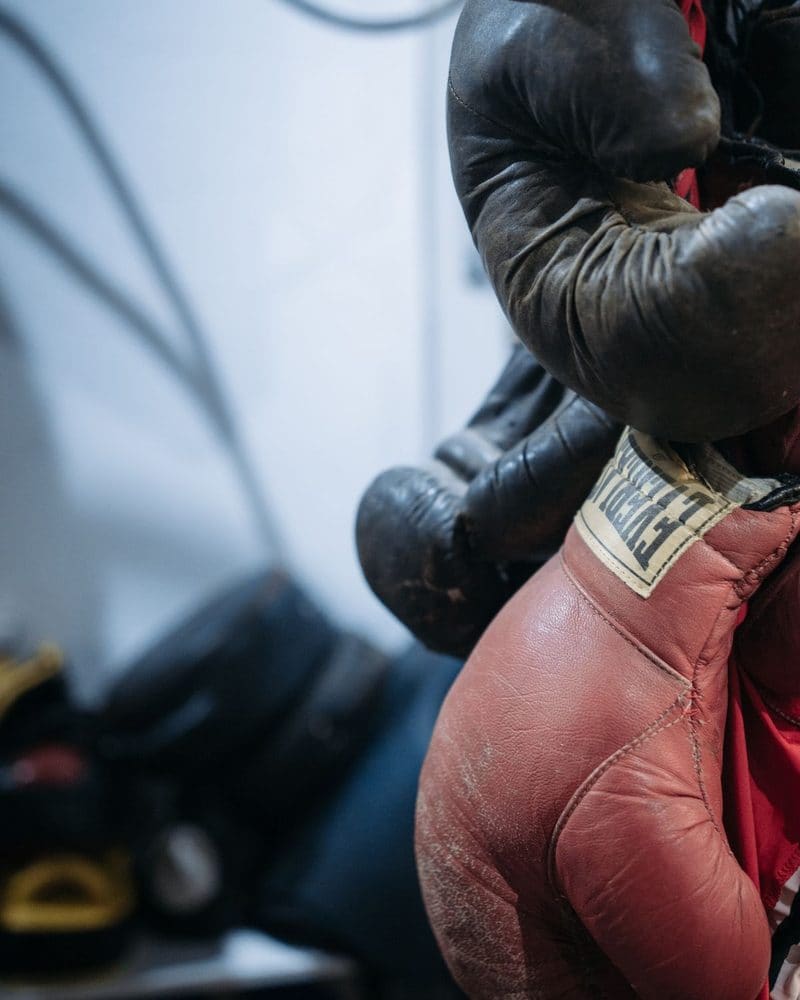 Worn red boxing gloves hanging on a hook