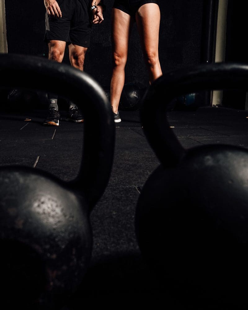 Kettlebells on the floor in front of two people at the start of a class