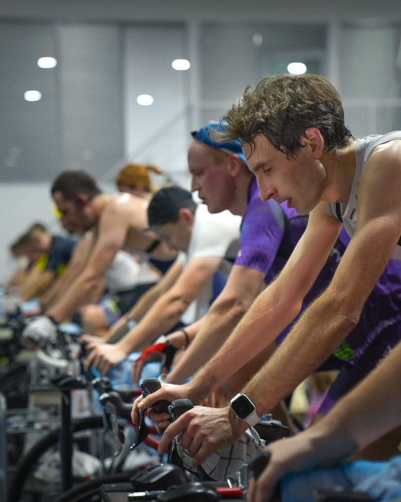 A row of riders on indoor bikes in the ride room