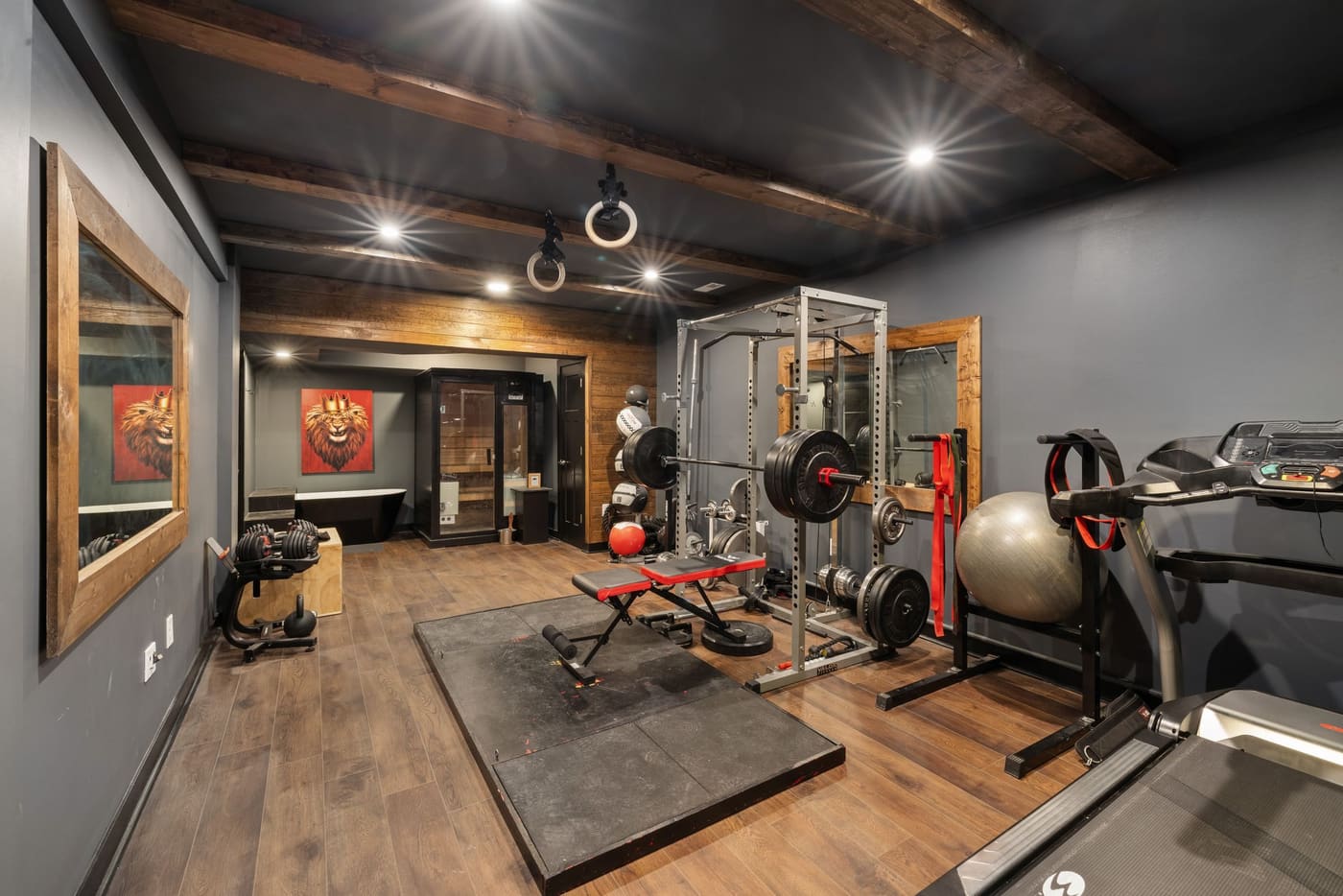 A strength training room with racks, a bench and a timber feature wall under spotlights