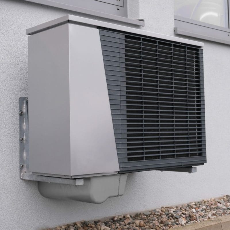 A heat pump unit mounted on the outside wall of a house
