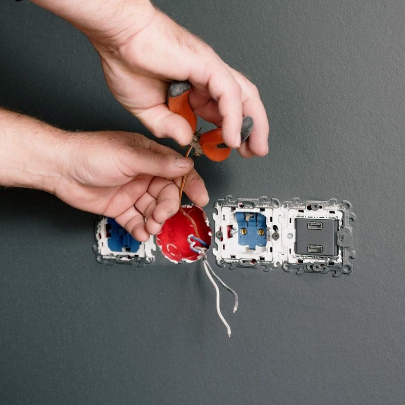 Hands wiring a new power point into a wall plate