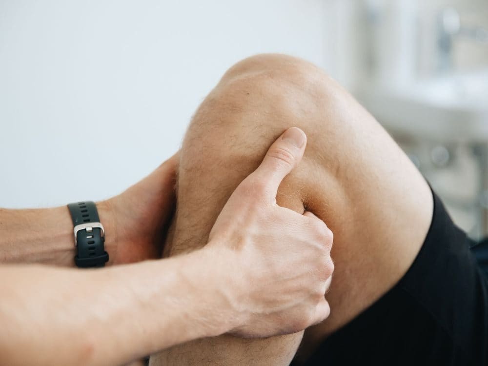 A physiotherapist working on the muscles above a patient's knee