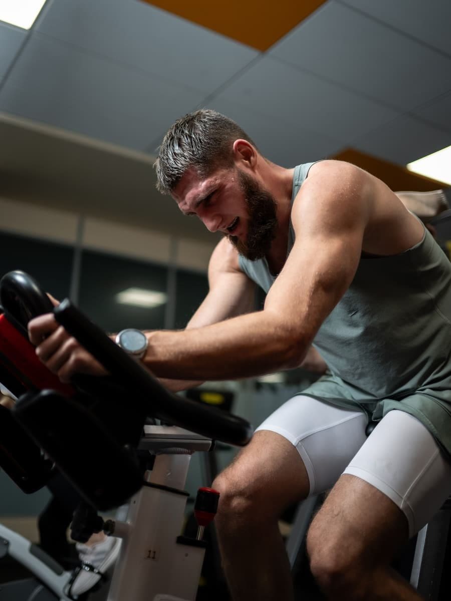 A man riding hard on an indoor bike in a dim studio