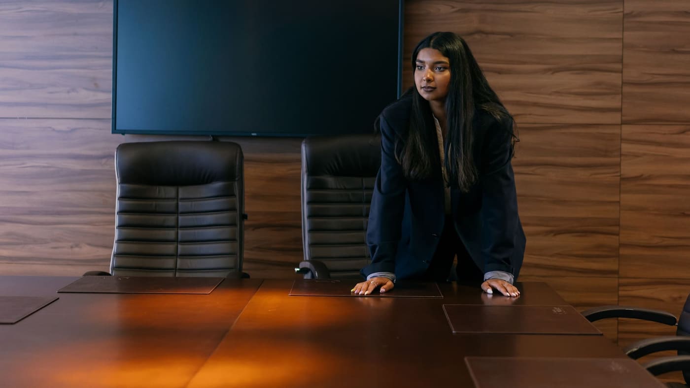 Morgan Sample standing at the head of a long boardroom table in a wood-panelled room