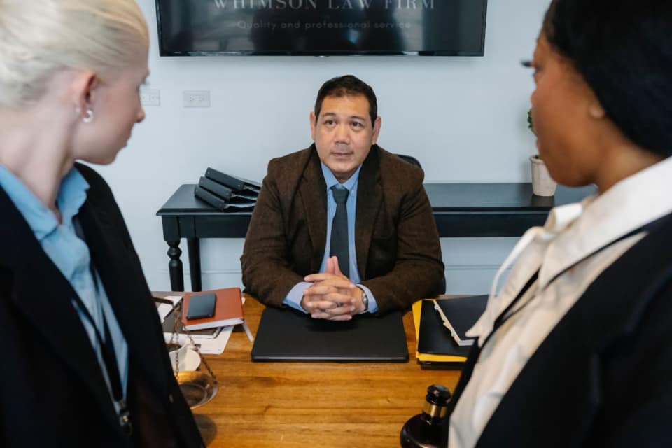 A lawyer at a wooden desk listening to two clients