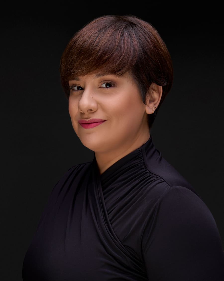 Harper Sample, a woman with short dark hair in a black top, against a dark background