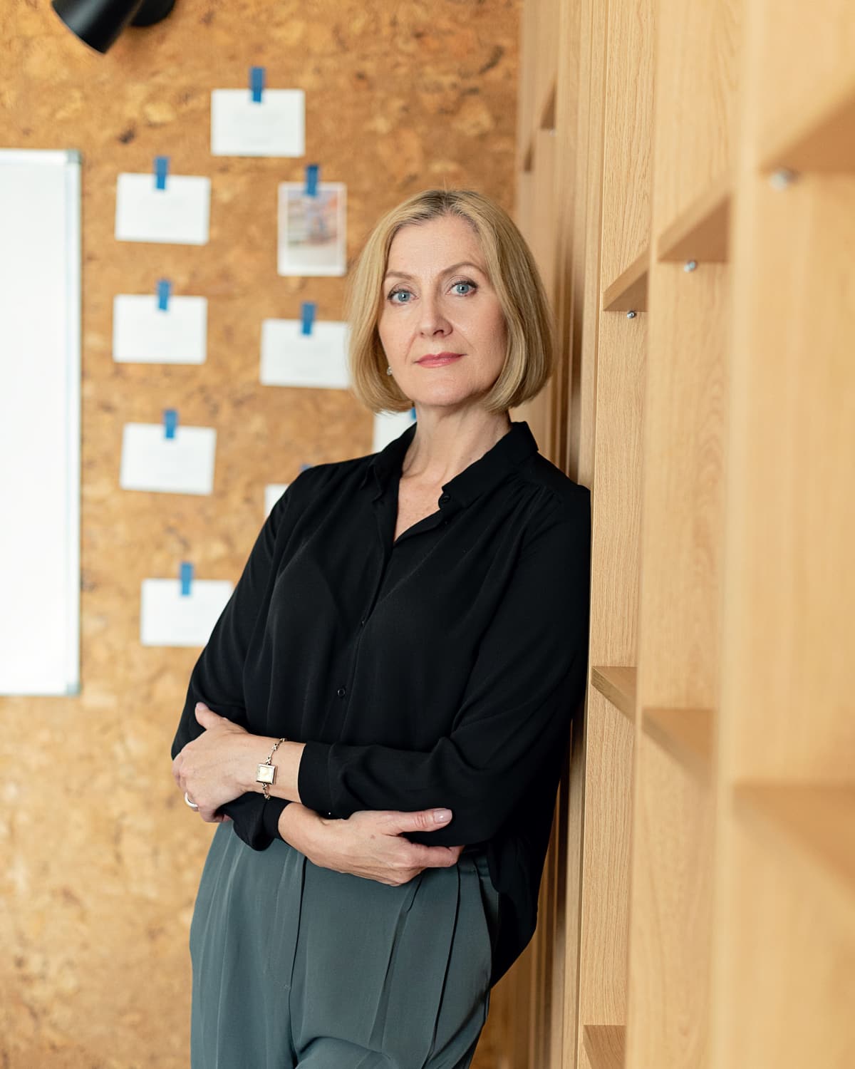 Jamie Sample standing beside a shelf in a bright office, arms folded