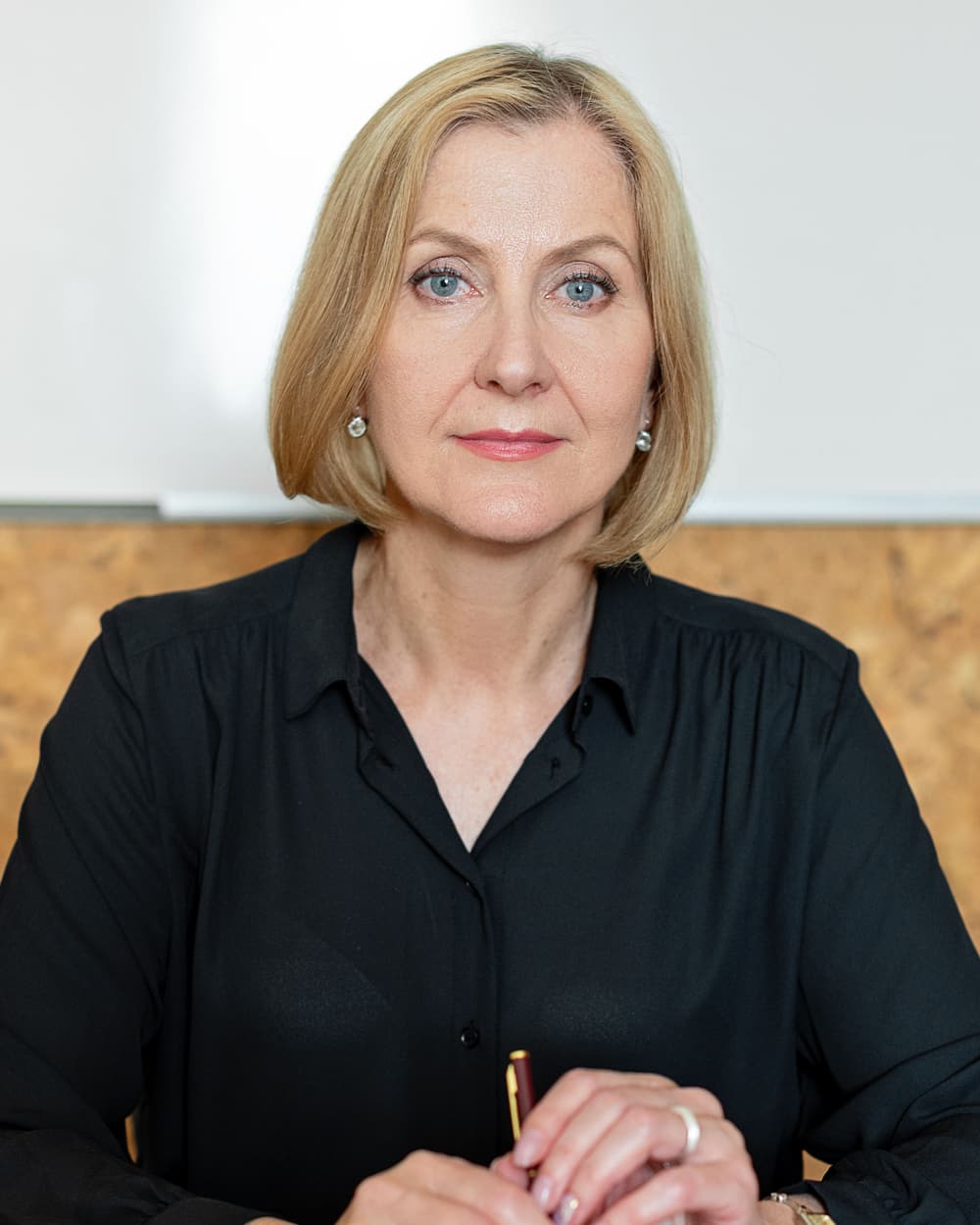 Jamie Sample sitting at a desk in a black blouse, hands resting on papers