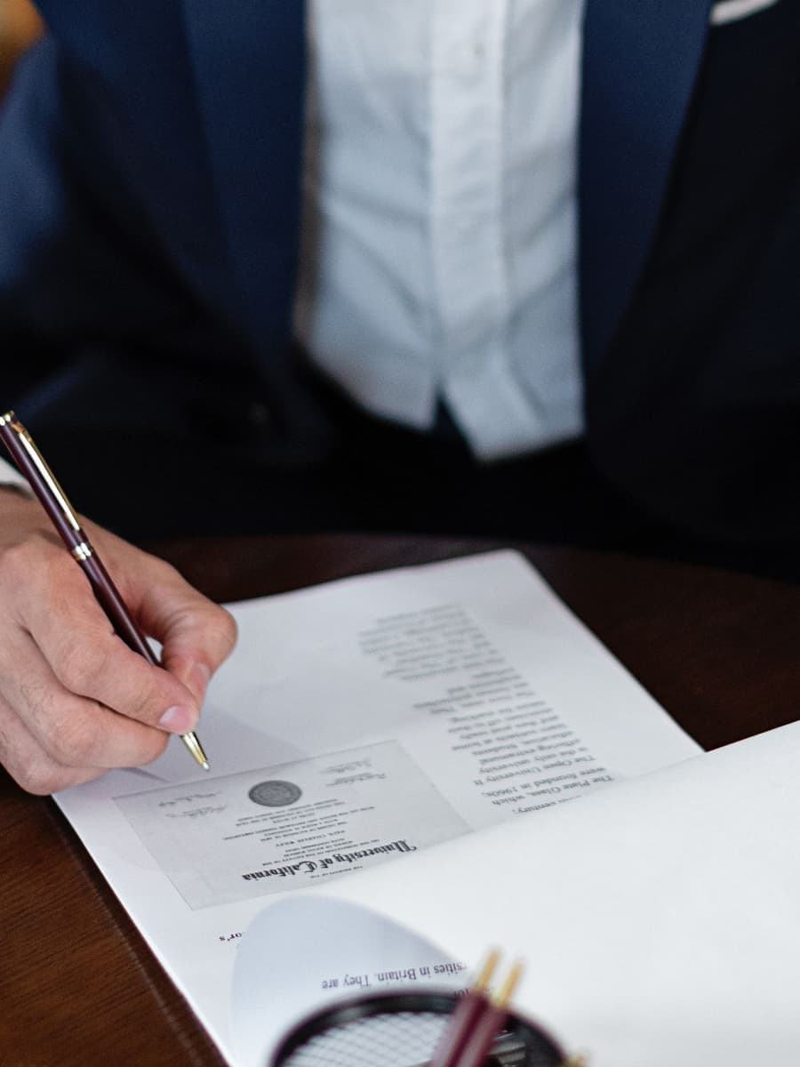 A lawyer's hand signing a document at a wooden desk