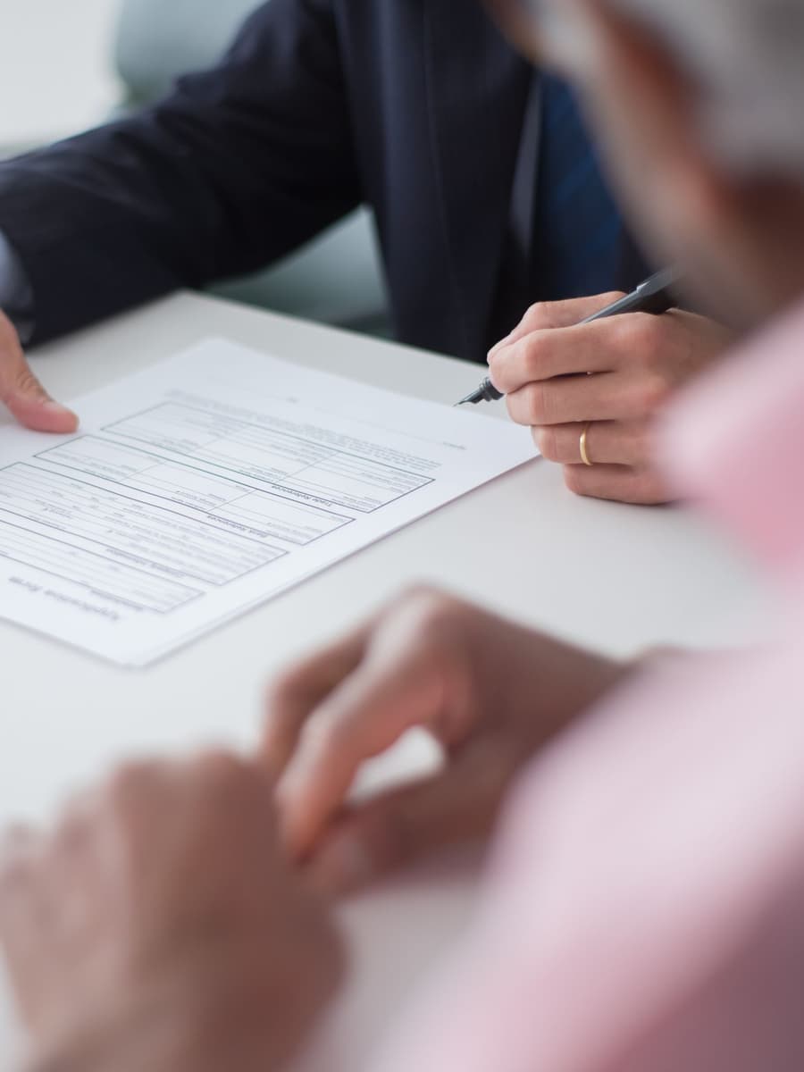 Two people going over a printed form at a white table