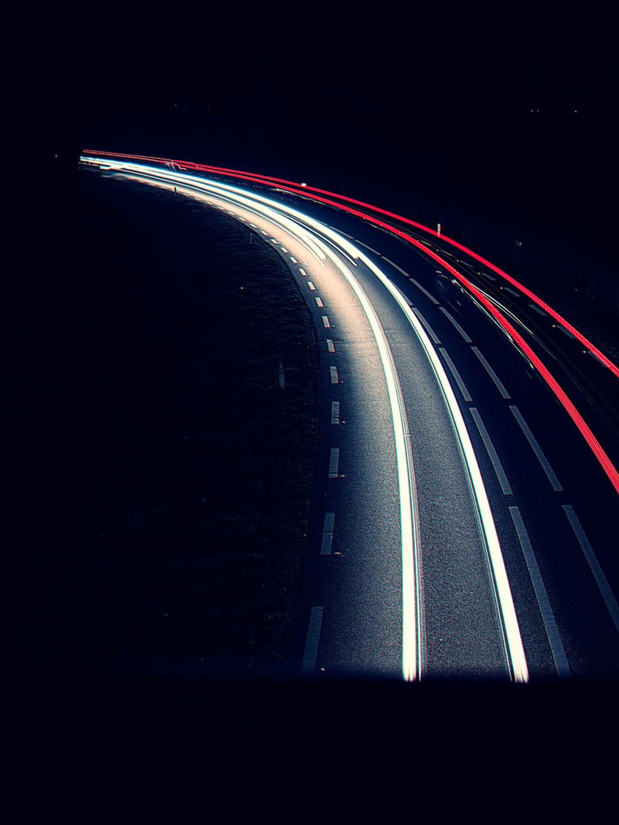 Light trails from cars on a dark road at night
