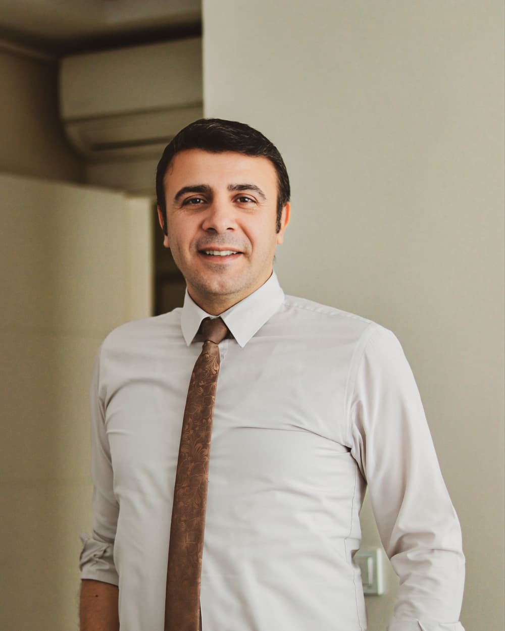 Jesse Sample in a shirt and tie, smiling, in an office
