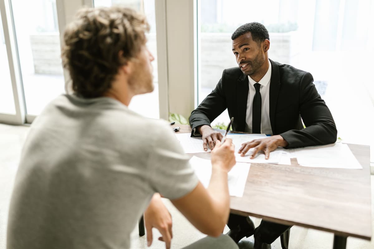An accountant in a dark suit going through papers with a client across a table