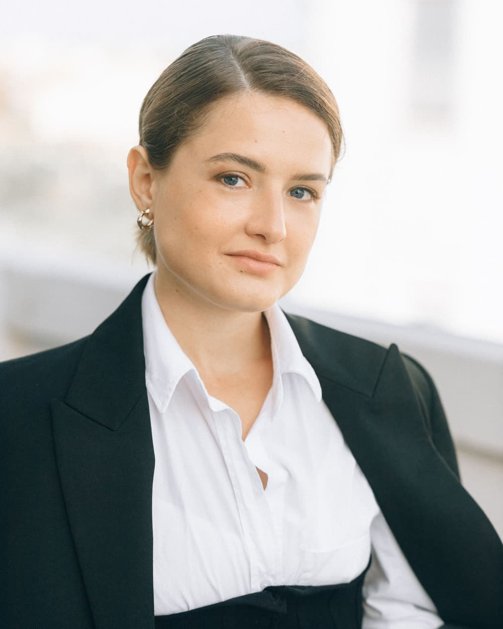 Sam Sample in a black blazer and white shirt, against a light wall