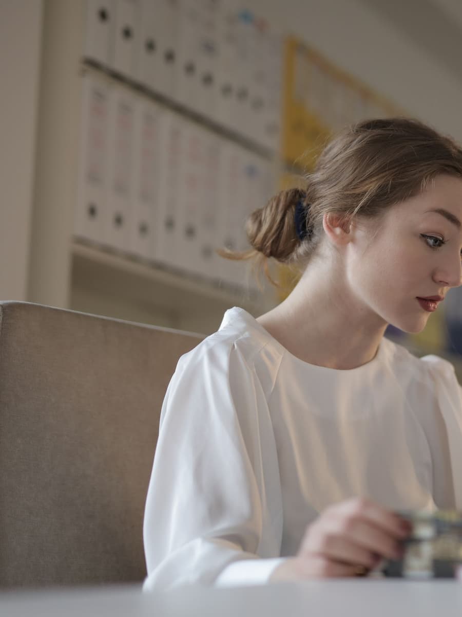 A young woman working at a laptop at a white desk